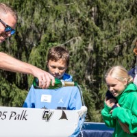 John Palk pours champagne on boat and family watches him